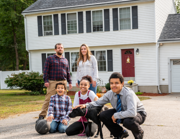 Family smiling in front of home