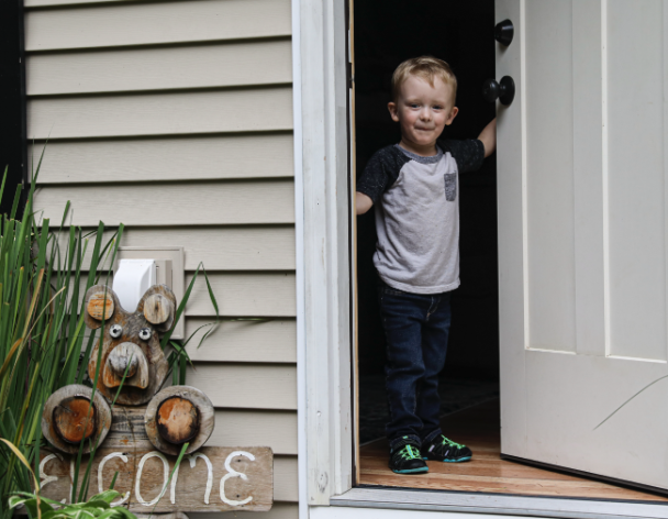Boy opening front door in greeting