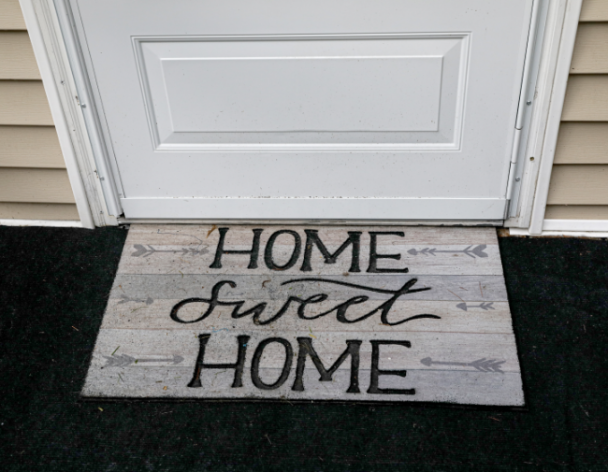 Picture of Welcome mat in front of door that says Home Sweet Home